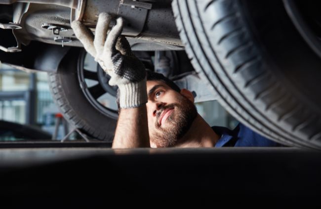 True Blue Mobile Mechanics Sydney technician inspecting a vehicles exhaust system. Mobile mechanic specialising in muffler repairs and underbody inspections