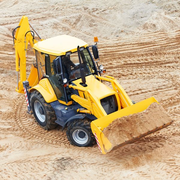 Backhoe loader working on a cleared rural block at Rural Property Services NSW showing excavation earthmoving site preparation and grading work