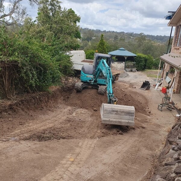 Excavation and site preparation in Western Sydney with excavator cutting and levelling ground beside a residential property by West Sydney Landscapes