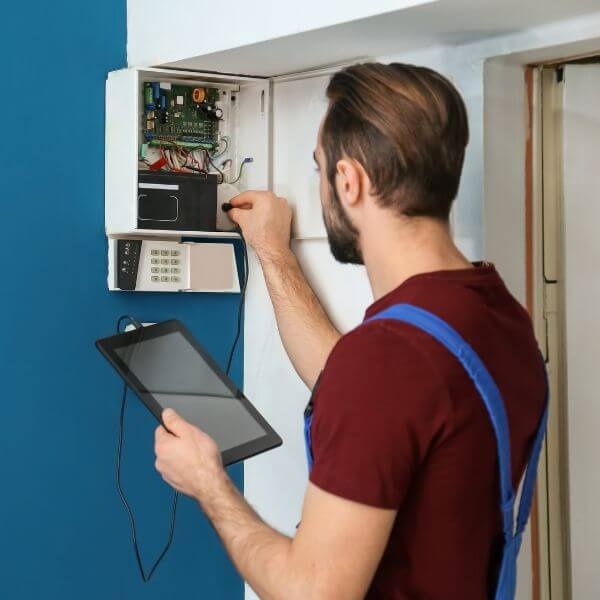 Home Security Guys performing home security alarm system repairs in Sydney inspecting internal wiring and control panel faults on a residential alarm system